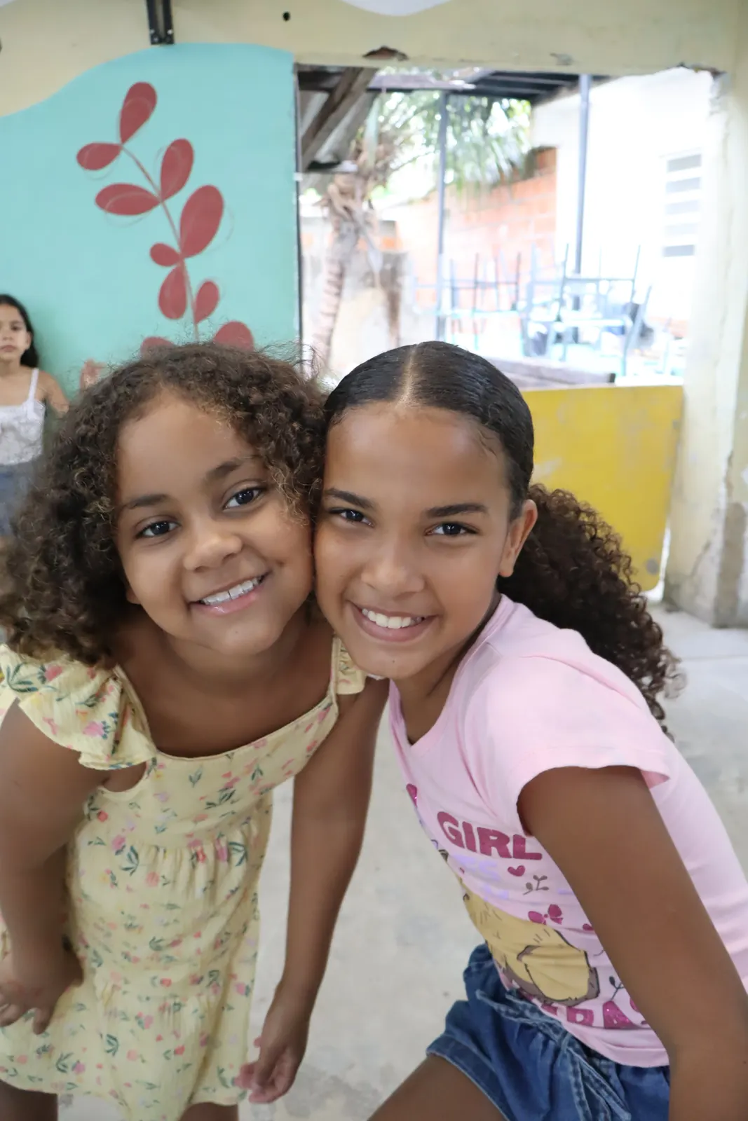 Duas meninas abraçadas sorrindo para a foto
